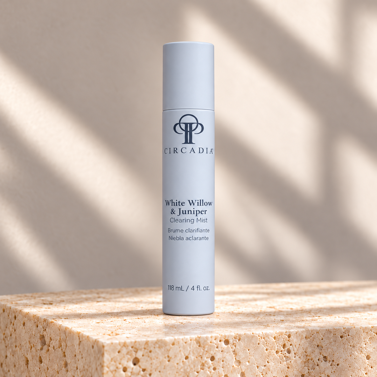 A cylindrical skincare bottle labeled 'Circadia White Willow & Juniper Clearing Mist' stands on a textured stone pedestal in warm natural light with soft shadows.